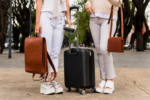 Two women standing with luggage at the airport.