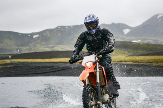 Man on motorcycle riding through shallow water